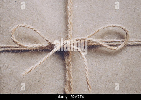 String or twine tied in a bow on kraft paper texture Stock Photo