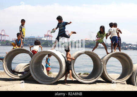 Children play tag on concrete pipes in the slums area of Baseco Compound in Tondo, Manila, Philippines. Stock Photo