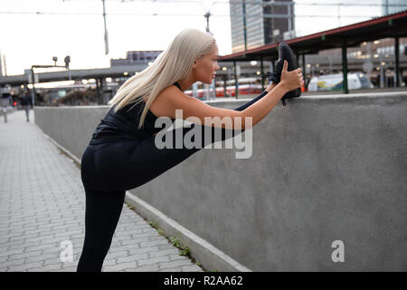 Pretty Woman Doing Stretching Exercise At Sidewalk Railing Stock Photo