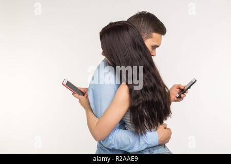 Smartphone addiction concept - Young couple using internet on mobile phone, ignoring each other. They are bored and sad Stock Photo