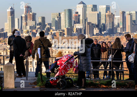 Greenwich Park, London, UK, 18th Nov 2018. People stand and watch the sunset by the General Wolfe statue, with panoramic views from the hilltop towards Canary Wharf. Stock Photo