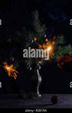 Sparklers on the background of the Christmas tree. Beautiful card. Bengal fire on a dark background. Stock Photo