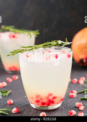 Autumn and winter cocktails idea - white sangria with rosemary, pomegrante and lemon juice and ingredients on black cement background. Stock Photo