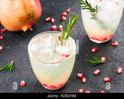 Autumn and winter cocktails idea - white sangria with rosemary, pomegrante and lemon juice and ingredients on black cement background. Stock Photo
