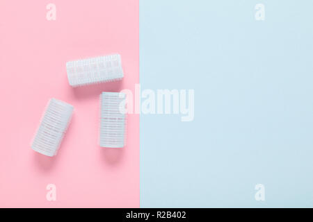 hair curlers on blue and pink paper background Stock Photo
