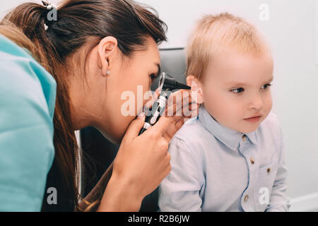 ENT doctor doing an ear exam with otoscope to little boy Stock Photo