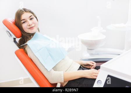 Dental clinic. Reception, examination of the patient. Teeth care. The girl is sitting in the dental chair ready to examine the teeth Stock Photo