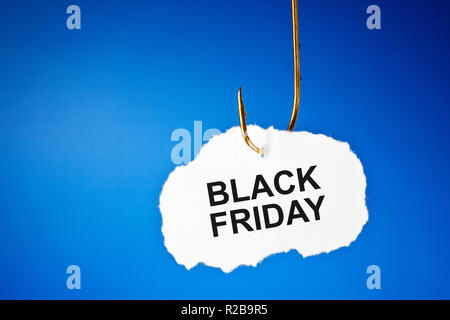 Text Black Friday hanging on a fishing hook over blue background. Beware of the Black Friday sale trap concept. Stock Photo