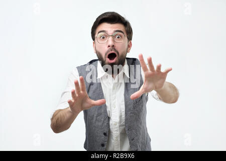 Crazy shocked young hispanic man with wide opened mouth, stretching hands ahead. Stock Photo