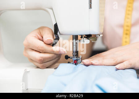 Sewing workshop. Seamstress at work. Young woman working with sewing machine. Stock Photo