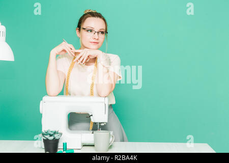 Sewing workshop. Seamstress at work. Portrait of a young dressmaker on a colored background. Stock Photo