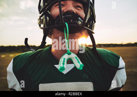 Closeup of a young American football player with his mouthguard hanging from his helmet during a team practice session Stock Photo
