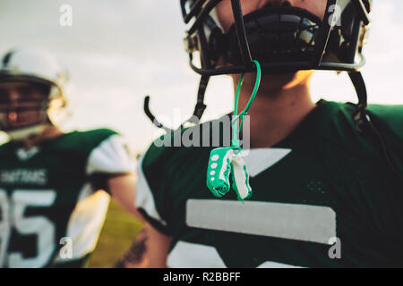 Closeup of a young American football player with his mouthguard hanging from his helmet during an afternoon practice Stock Photo