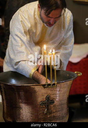 BUCHAREST, ROMANIA - October 27, 2018: Romanian christian orthodox priest officiating a baptism ceremony in the church Stock Photo