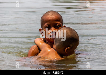 Don Khone, Laos - April 24, 2018: Local kids holding each other and swimming in the Mekong river Stock Photo