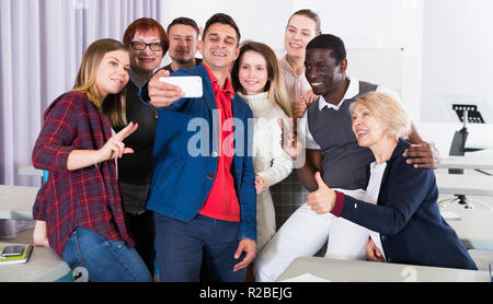 Friendly cheerful adult students of different nationalities making selfie in class Stock Photo