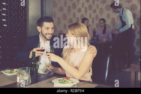 Young couple on romantic date drinking red wine in restaurant Stock Photo