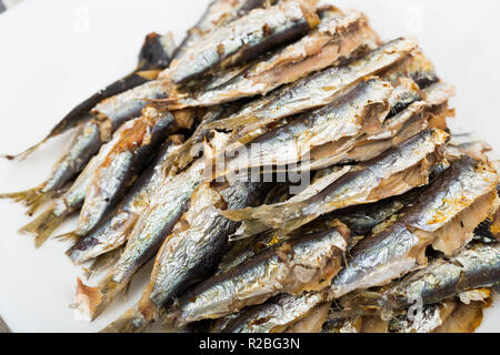 Seafood. Appetizing baked sardines served without garnish on white plate Stock Photo