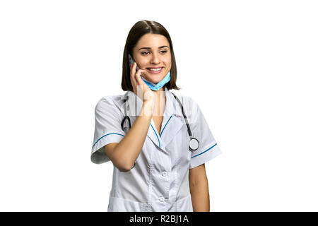Lady doctor talking on cell phone. Portrait of smiling female physician talking on mobile phone over white background. Medical service concept. Stock Photo