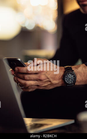 Close up of man hand using mobile phone with laptop on table. Business man using smart phone. Stock Photo