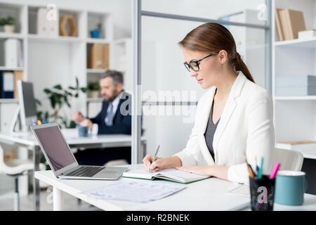 Serious lady making notes in diary Stock Photo