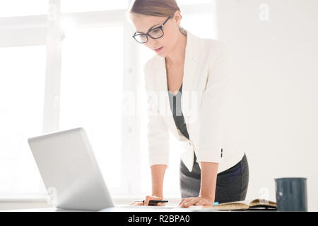 Concentrated female manager viewing data on laptop Stock Photo