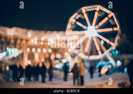 Blurred city with christmas lights at night. New Year bokeh background.  Urban night scene with defocused city lights, buildings and people. Design. C Stock Photo