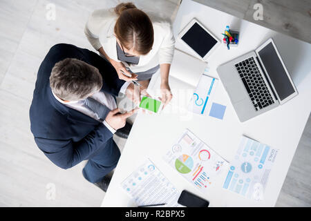 Modern business colleagues using mobile app and discussing infor Stock Photo