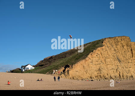 A young boy flies a kite on the beach at West Bay, Dorset. Stock Photo