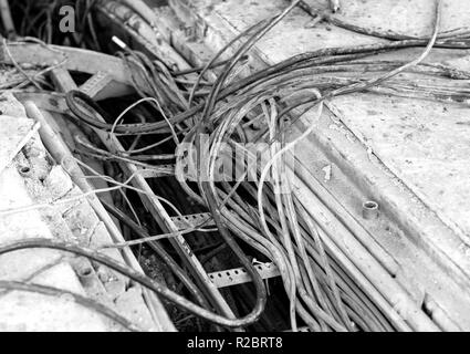 electric cable duct open, showing different thickness, with a dirty appearance in an industrial environment, waiting to be removed. Black and white ph Stock Photo