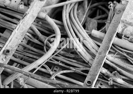 electric cable duct open, showing different thickness, with a dirty appearance in an industrial environment, waiting to be removed. Black and white ph Stock Photo