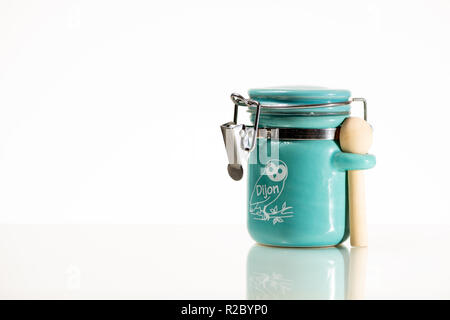 Closeup of a small mustard pot with wooden spoon from Dijon (France), white background Stock Photo