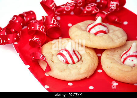 closeup of sugar cookies on red and white polka dot plate with striped candy and curly Christmas ribbon Stock Photo
