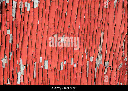 Old red paint peeling from a weathered exterior wall. Stock Photo