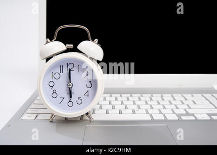 Alarm clock and portable computer put on the desk, with white background. Stock Photo