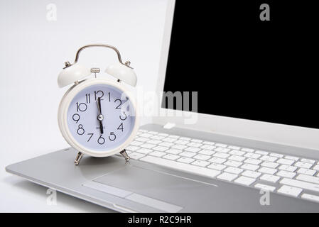 Alarm clock and portable computer put on the desk, with white background. Stock Photo