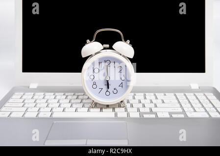 Alarm clock and portable computer put on the desk, with white background. Stock Photo