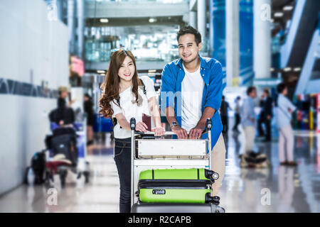 Asian couple traveler with suitcases at the airport. Lover travel and transportation with technology concept. Stock Photo
