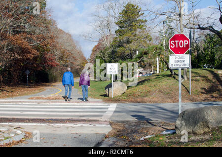 Couple walking on Shining Sea Bikeway  in Falmouth, Cape Cod at road crossing with Cyclists Dismount to Cross Street, No Motor Vehicles & Stop signs Stock Photo