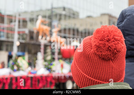 A woman wearing a red pom pom hat watches a Santa sleigh float in a holiday parade Stock Photo