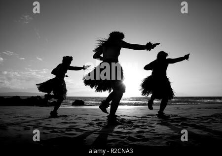 Three male hula dancers at sunset at Wailea, Maui, Hawaii. Stock Photo