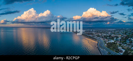 Breathtaking wide aerial panorama of beautiful clouds over ocean bay coastline at sunset Stock Photo