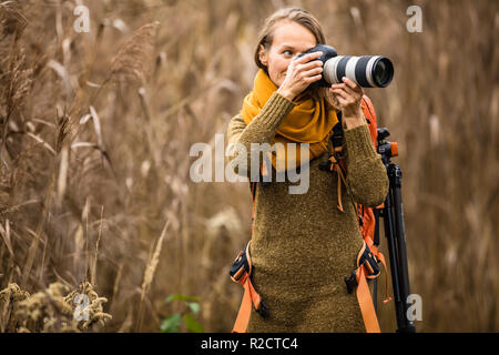 Pretty, female photographer taking pictures outdoor on a lovely autumn day - shallow DOF, color toned image