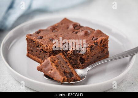 Piece of chocolate vegan cake with chocolate drops and nuts. Stock Photo