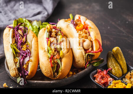 Hot dogs with assorted toppings on a dark background, top view. Traditional american food concept. Stock Photo