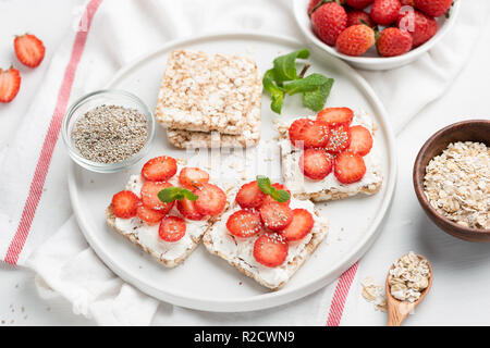 Rice crispbread with strawberries and curd cheese ricotta on white plate. Healthy snack, vegetarian food, healthy sweet appetizer or breakfast concept Stock Photo