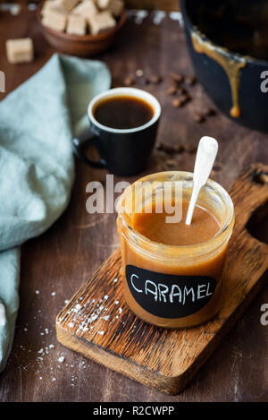 Salted caramel sauce in jar on wooden table. Homemade caramel Stock Photo