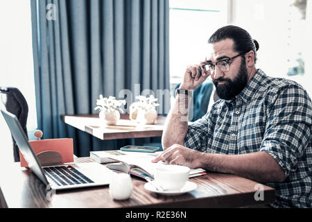 Bearded freelancer feeling overloaded having too many tasks Stock Photo