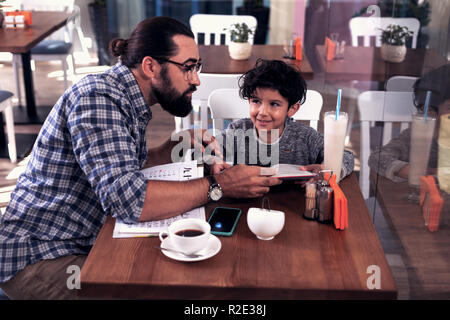 Professional English tutor teaching little cute boy in the cafeteria Stock Photo
