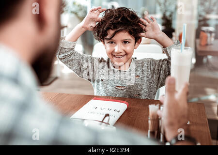 Happy son drinking milk shake spending time in cafeteria with father Stock Photo
